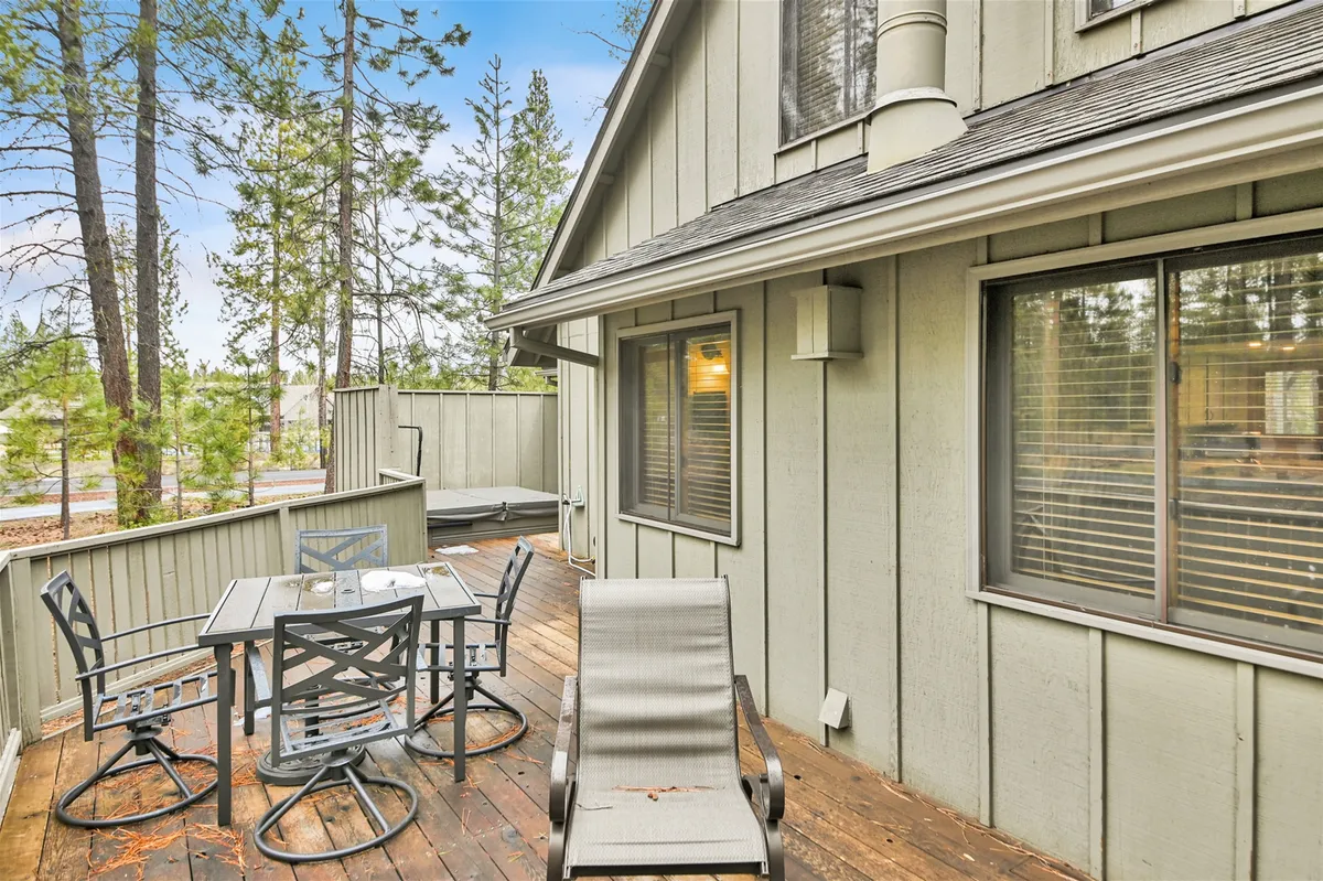 A tranquil patio scene with a table and outdoor chairs surrounded by trees, perfect for family gatherings, meals, or relaxing after a day of recreation. The setting captures the peaceful Sunriver environment and the promise of outdoor fun.