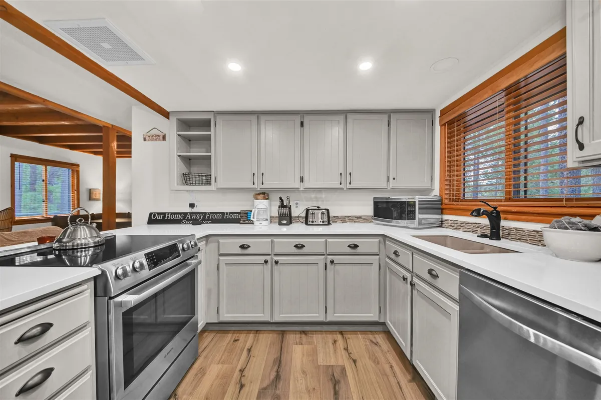 A bright kitchen space with a stylish island, stainless steel appliances, and natural light streaming through the window. The scene highlights modern updates and a welcoming spot for sharing meals or preparing a romantic dinner.