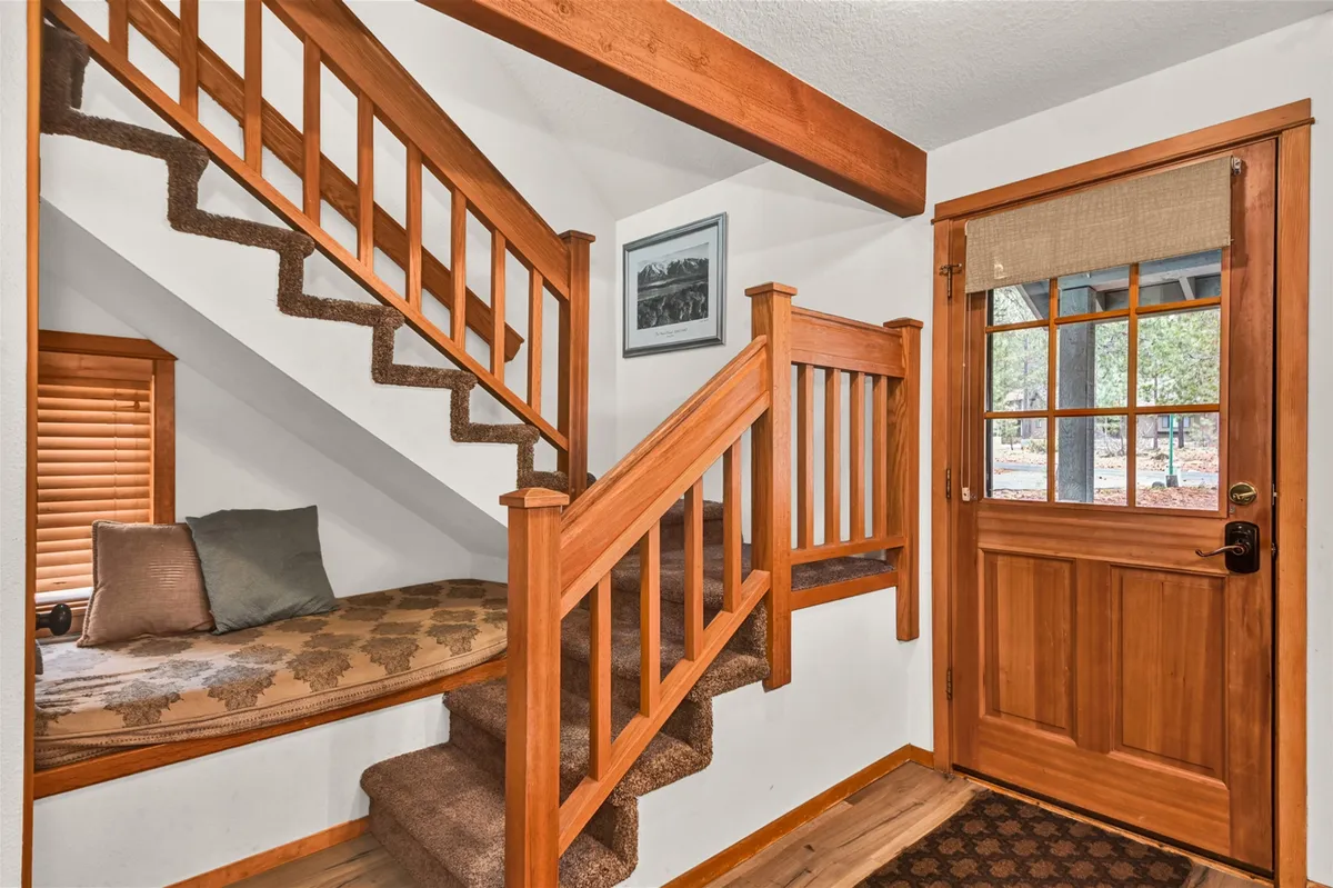 A welcoming entryway featuring a staircase, a cozy window seat, and the front door, all bathed in natural light. This transitional space connects the inside of the home to the outside, suggesting both arrival and departure for nearby adventures.
